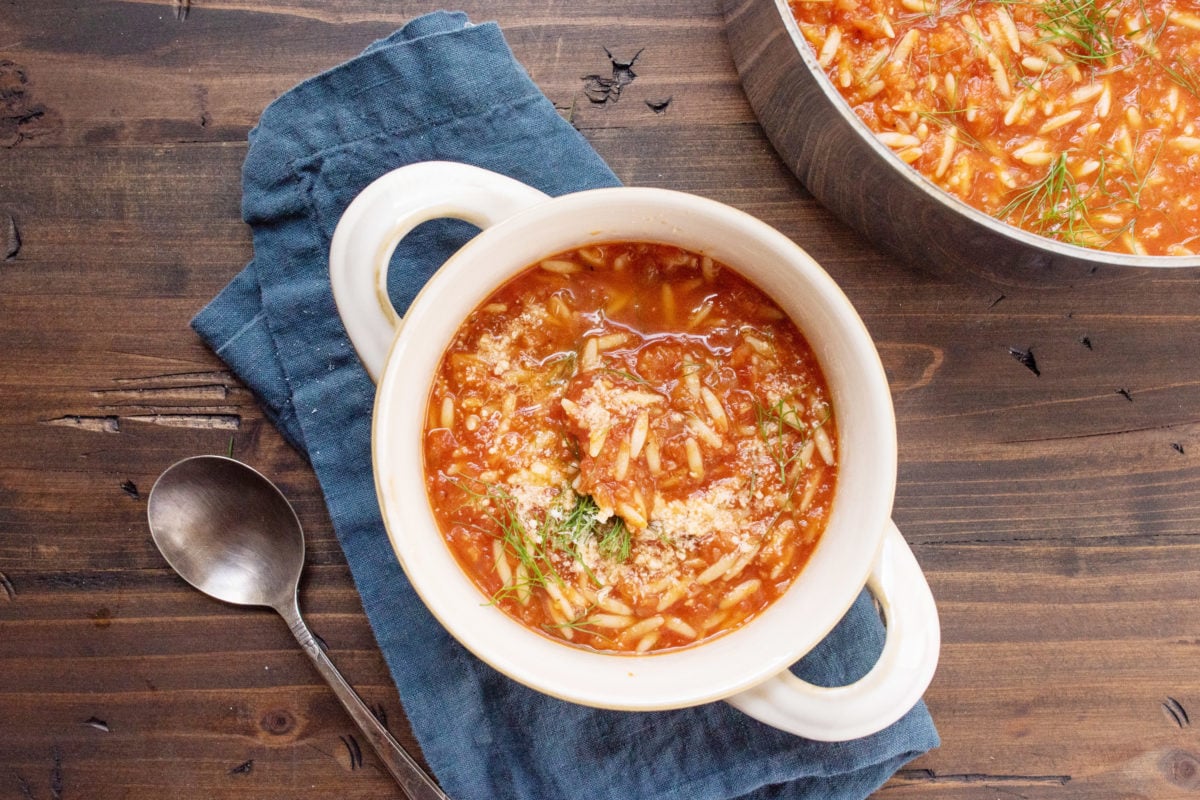 Bowl of Tomato, Orzo and Dill Soup on a blue cloth napkin.