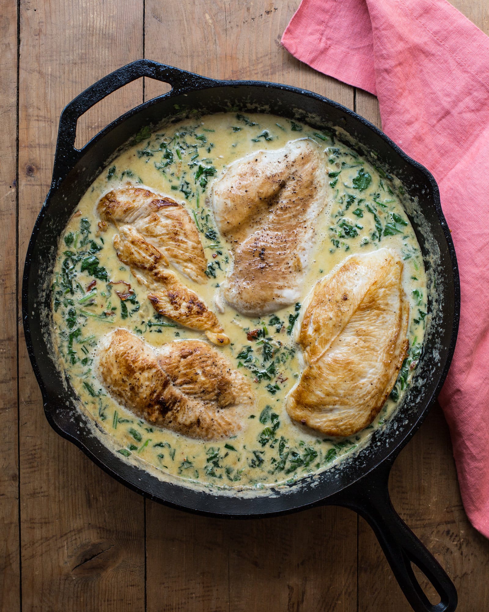 Cast iron skillet with chicken in creamy spinach and sun-dried tomato sauce.