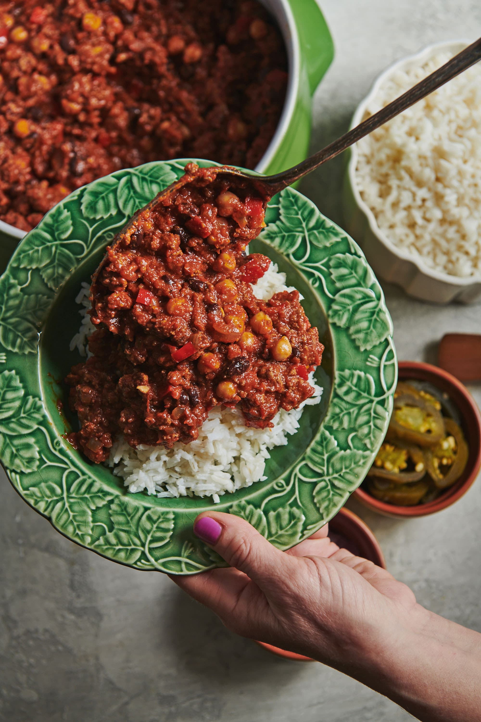 Spoon serving Ground Beef Chili over rice.