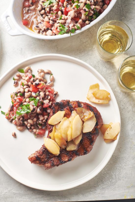 Pork Chops with Apples and Black Eyed Pea Salad on a white plate.