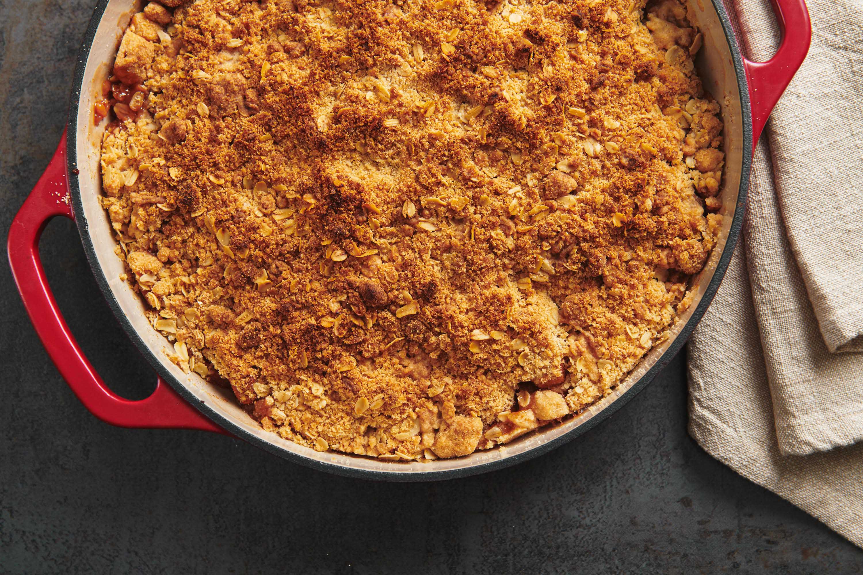Baked streusel apple crisp in red dish on table.