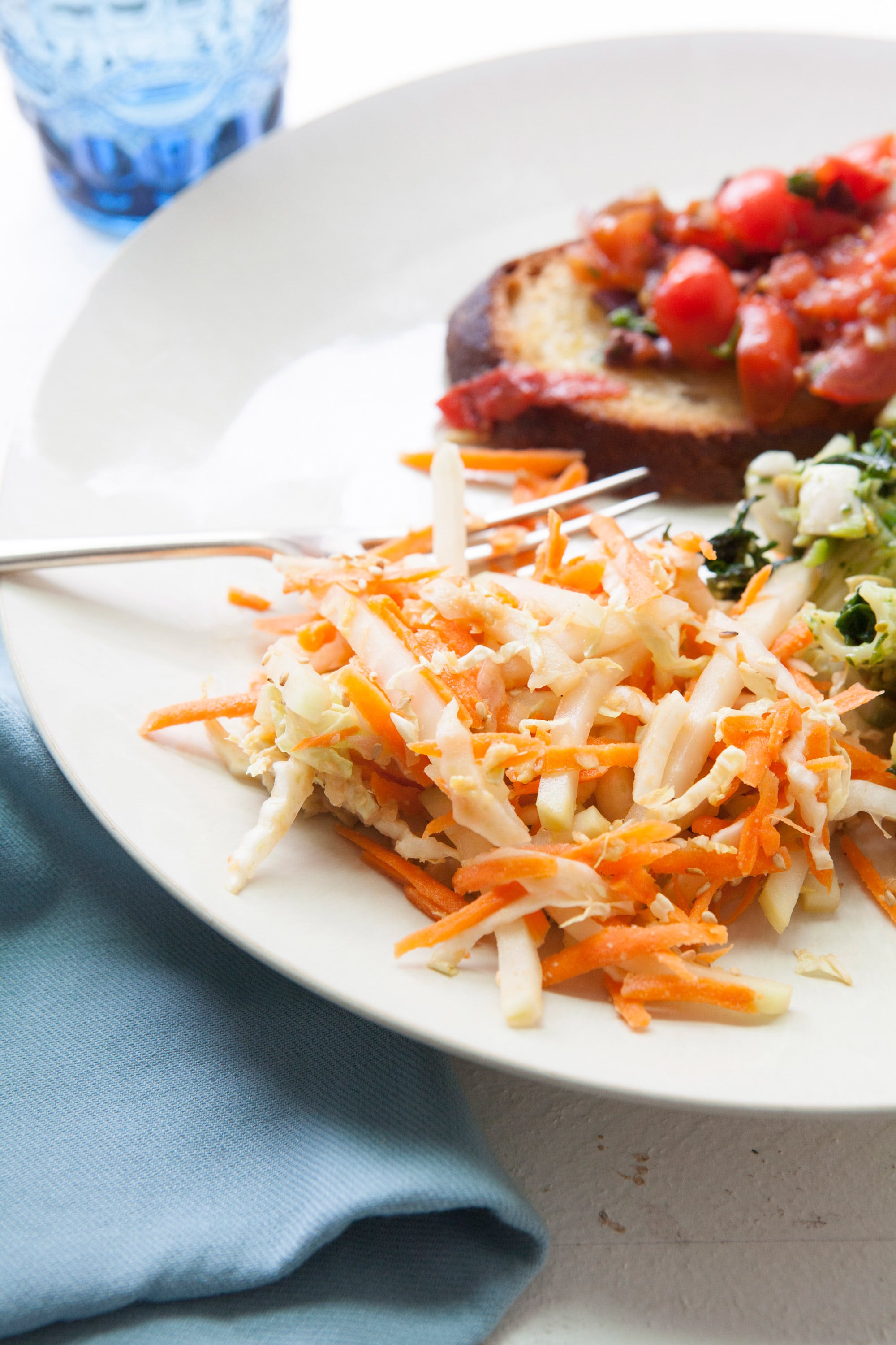 Carrot, Cabbage and Kohlrabi Slaw with Miso Dressing on white plate with fork.