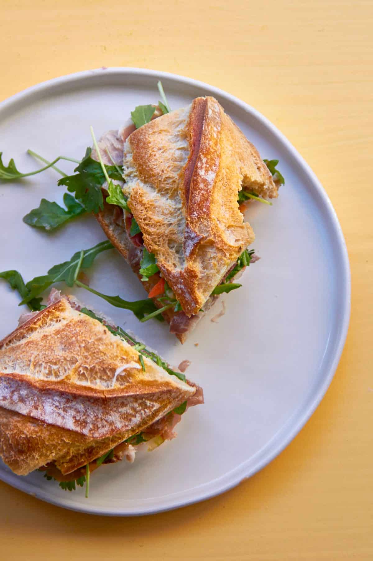 Sliced Prosciutto and Pork Banh Mi on white plate.