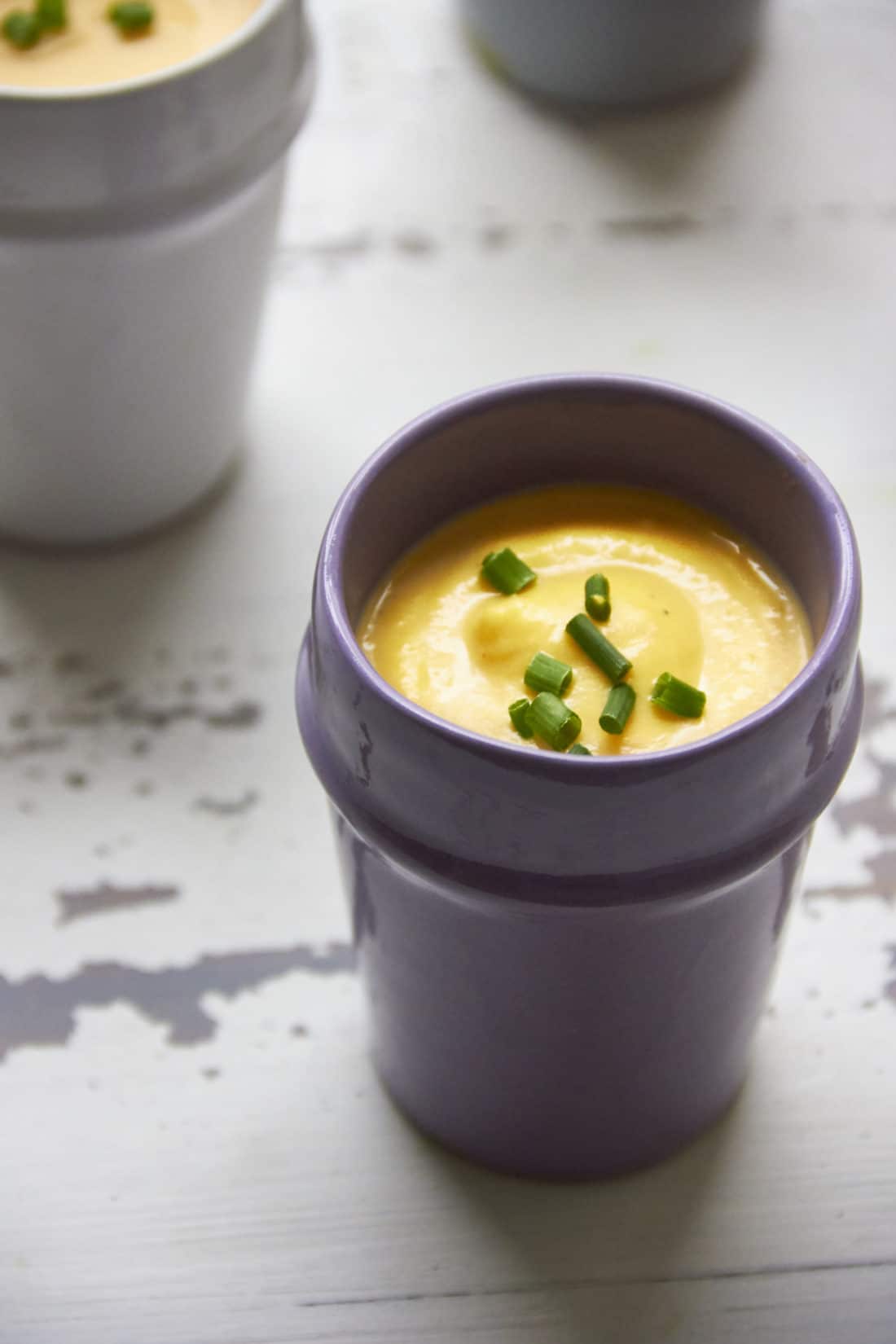 Purple cup of Butternut Squash and Fennel Soup topped with chives.