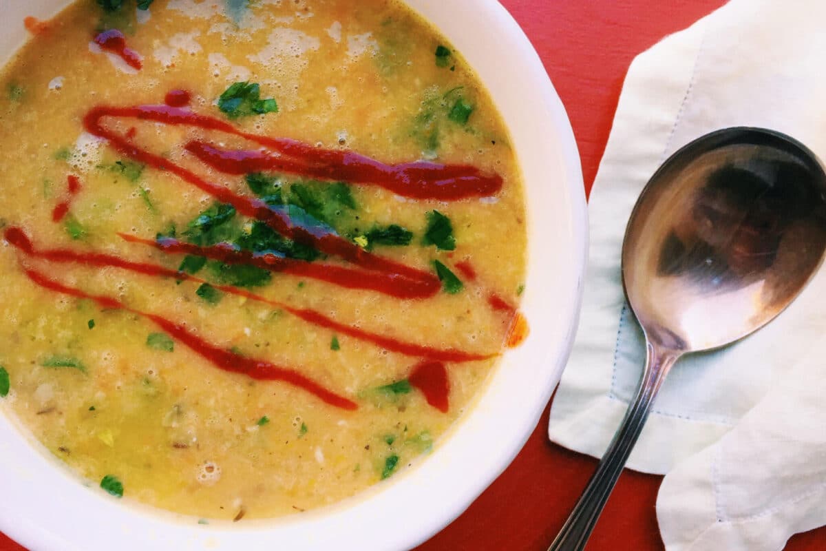 Chunky Chickpea Soup in white bowl next to spoon.