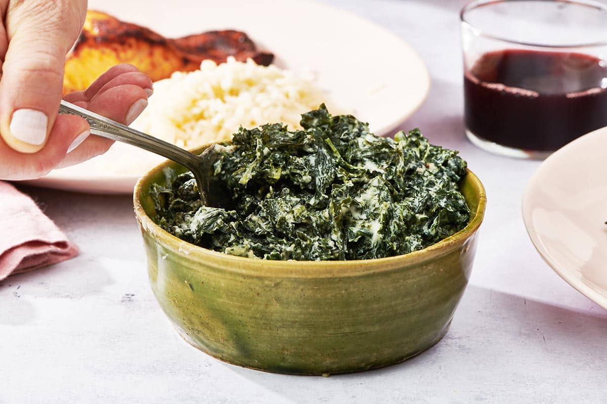 Creamed Kale and a fork in a green bowl.