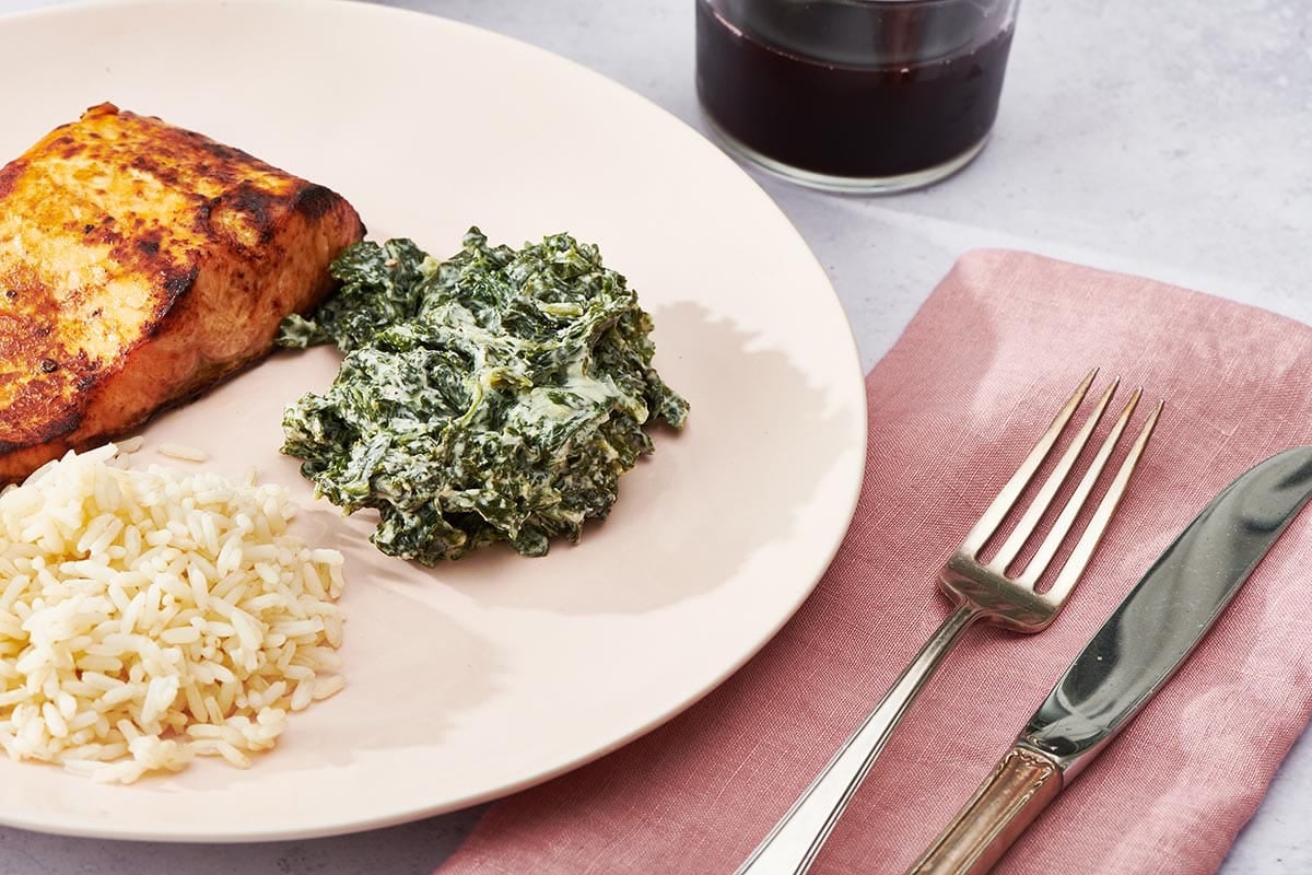 Creamed kale on plate with salmon and rice.