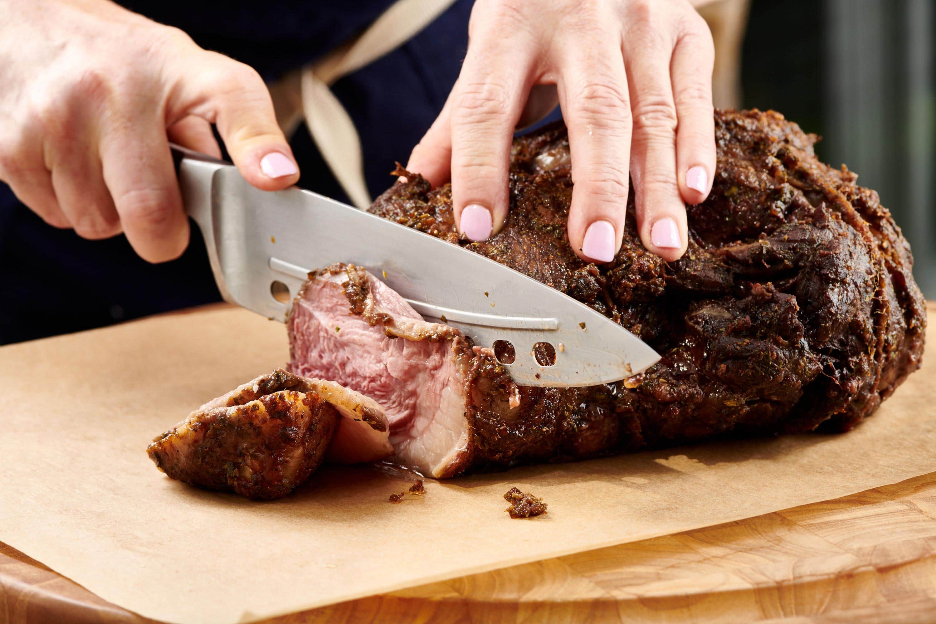 Woman slicing a Moroccan Leg of Lamb with a knife.