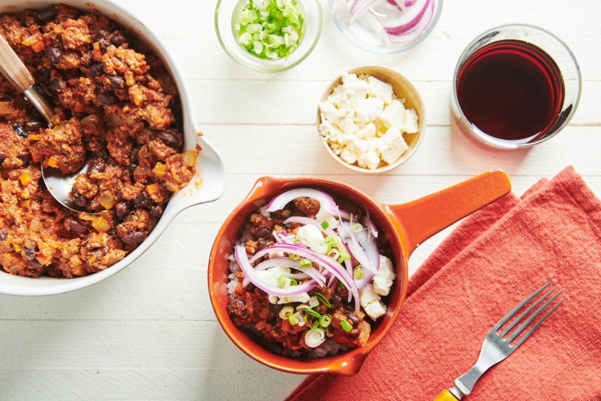 Bowl of Beef, Black Bean, and Jalapeno Chili topped with onion, scallions, and cheese.