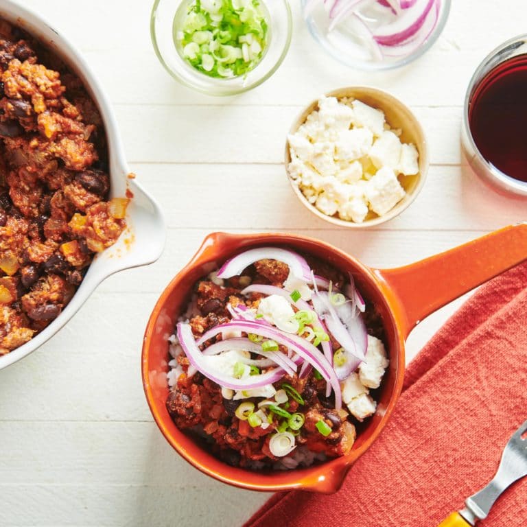 Bowl of Beef, Black Bean, and Jalapeno Chili topped with onion, scallions, and cheese.
