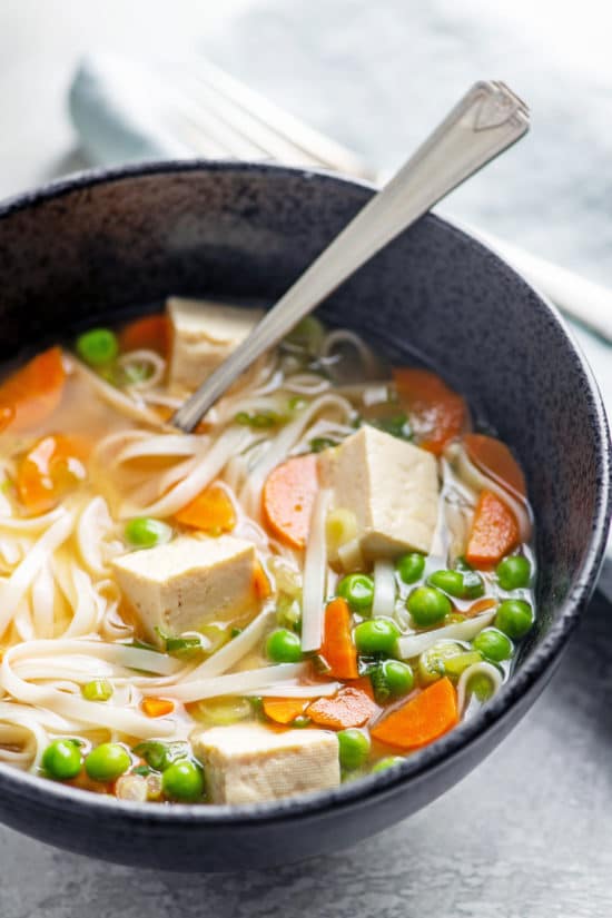 Spoon in a bowl of Vegetable Udon Noodle Soup.