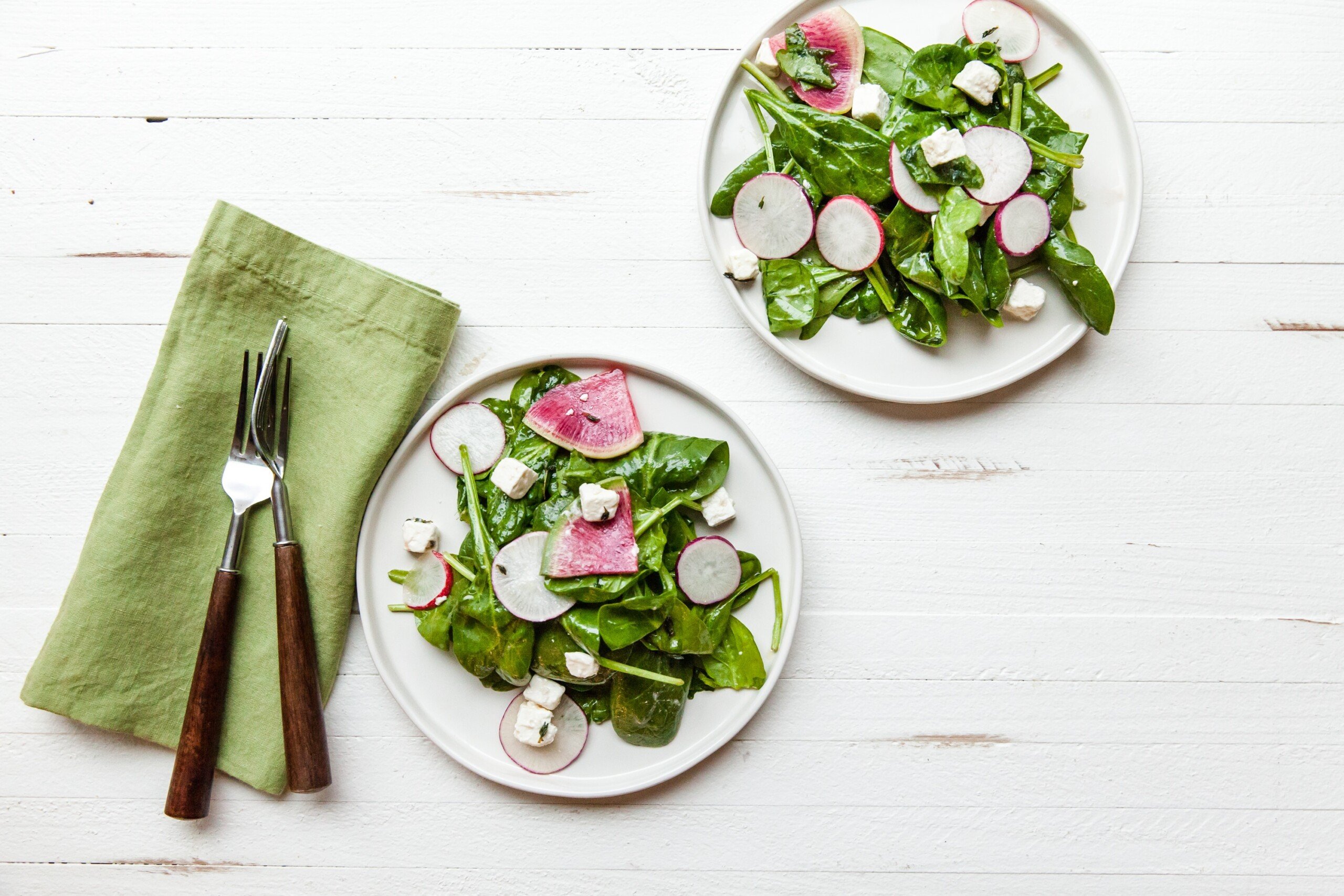 Spinach and Radish Salad with Feta on white plates.