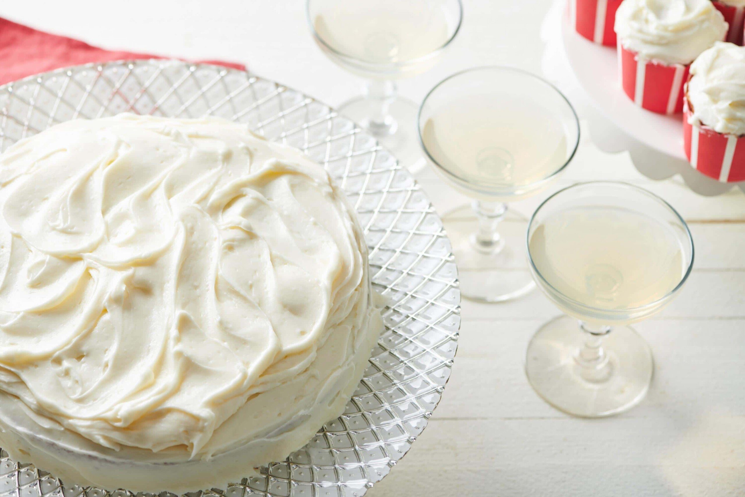 Platter of Banana Cake with Cream Cheese Frosting on a white, wooden table.