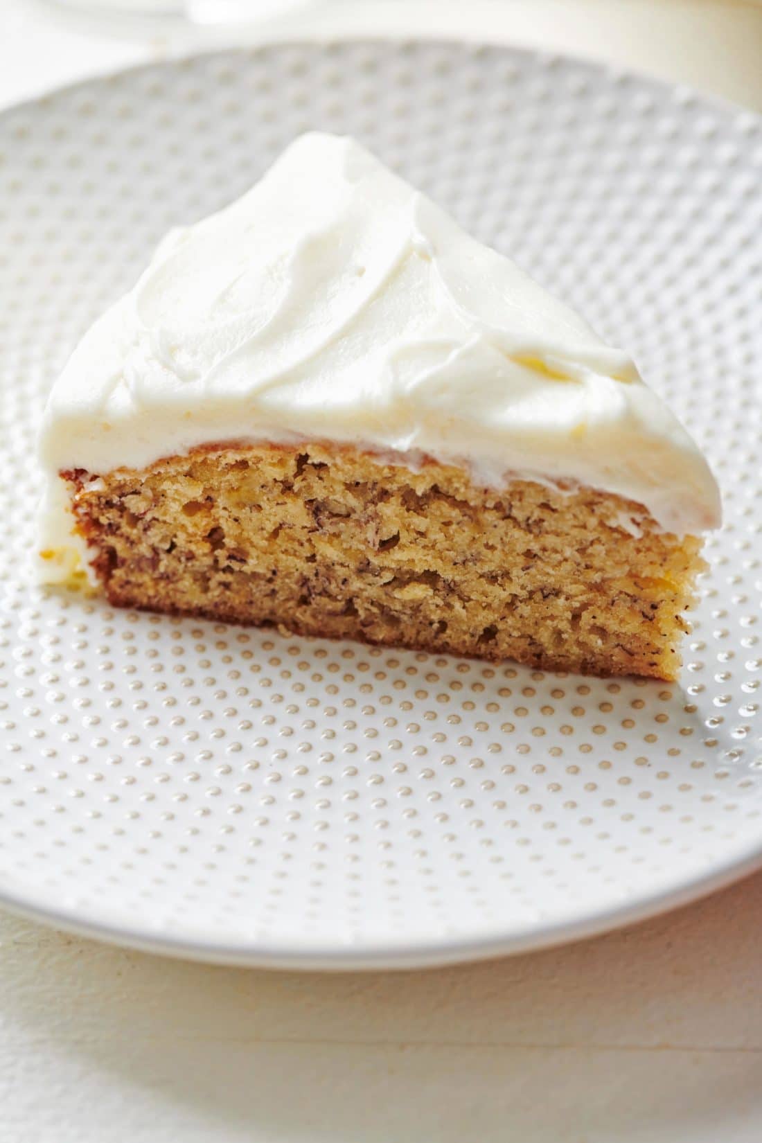 Slice of Banana Cake with Cream Cheese Frosting on a plate.