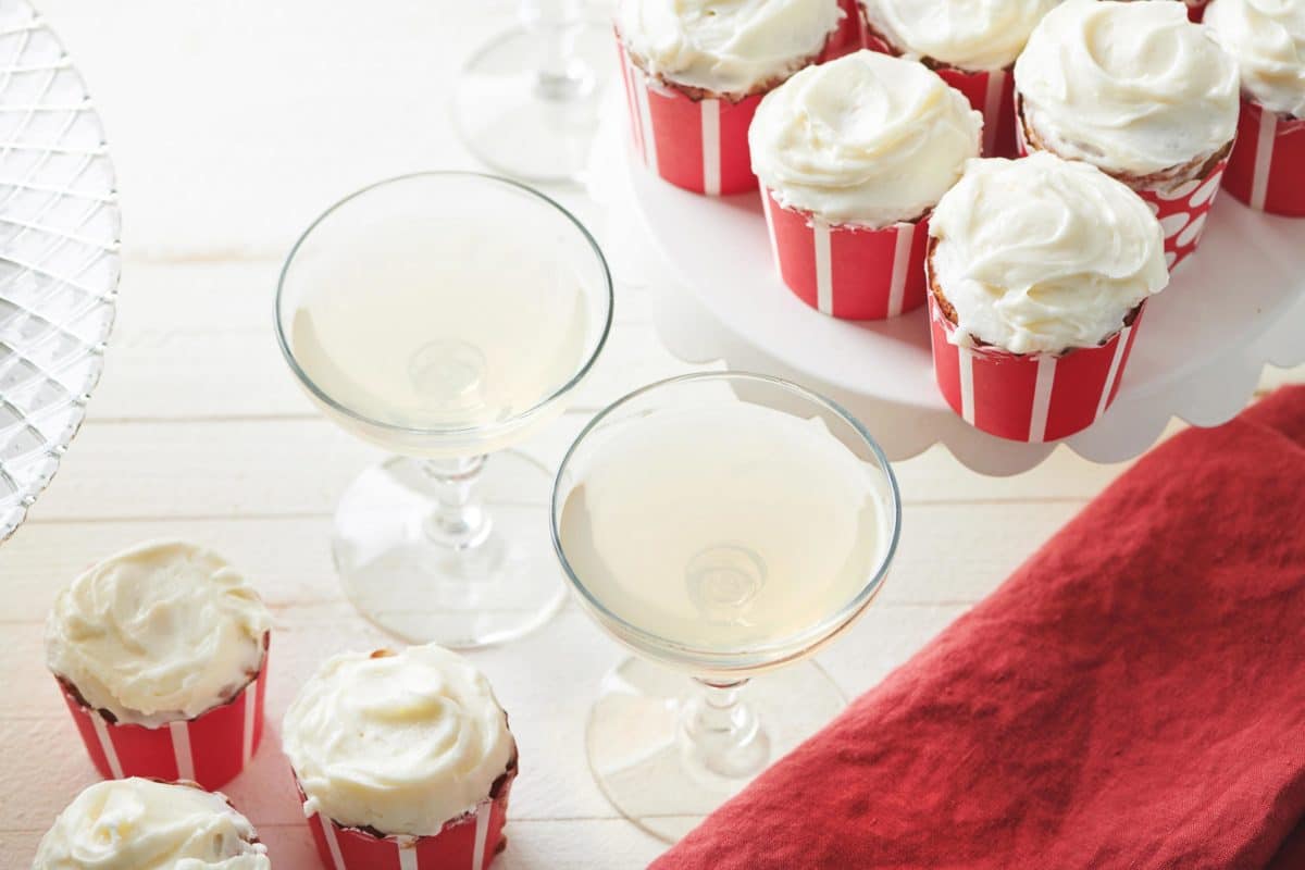 Stemmed glasses surrounded by Banana Cupcakes with Cream Cheese Frosting.