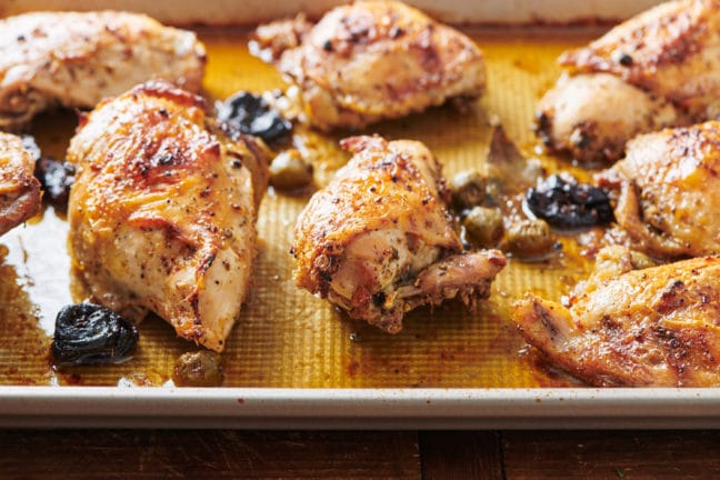 Lined baking sheet with Chicken Marbella.