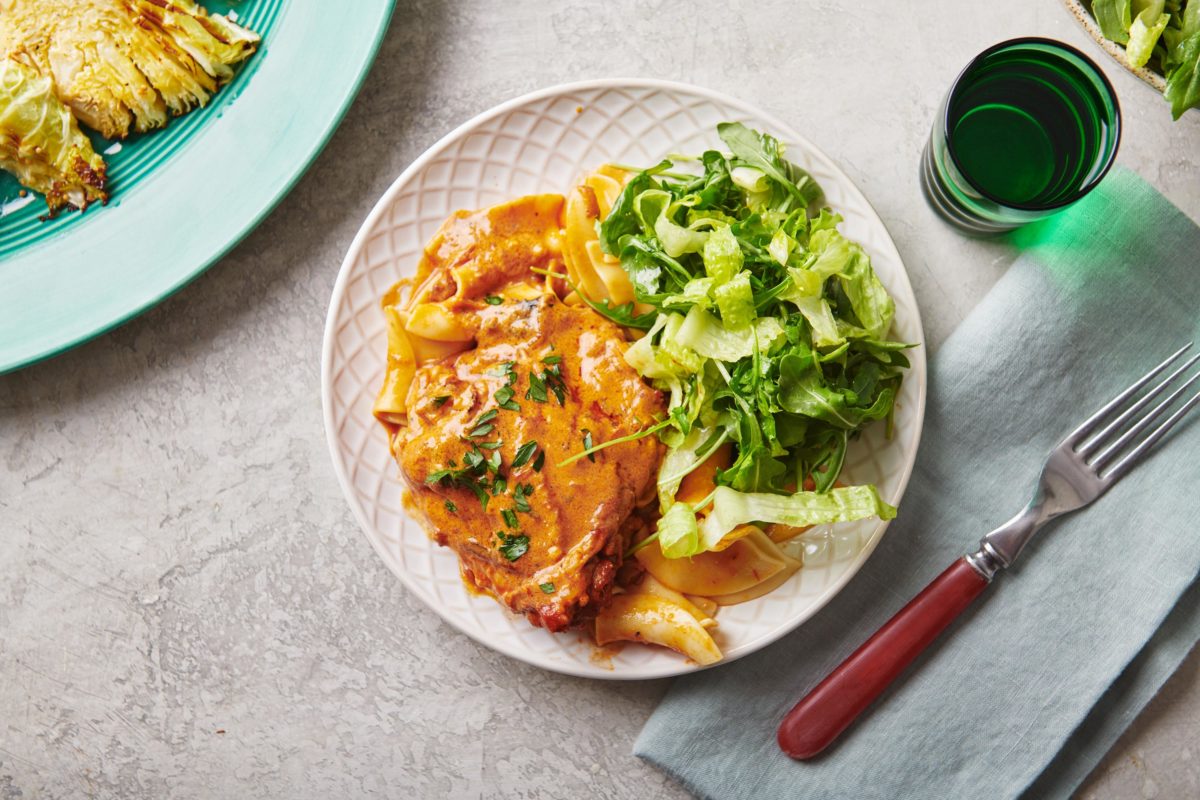 Chicken Paprikash on a plate with salad.