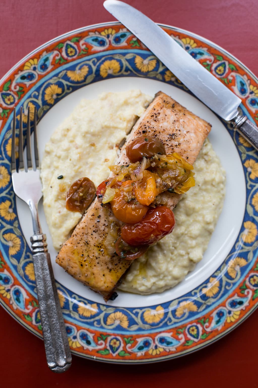 Salmon with Polenta and Warm Tomato Vinaigrette on a colorful plate.