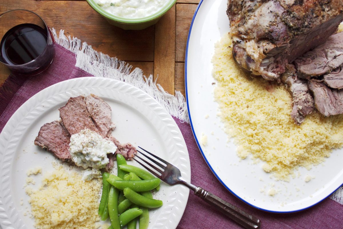 Plate with couscous, peas, and slices of Mediterranean Leg of Lamb with Tzatziki.