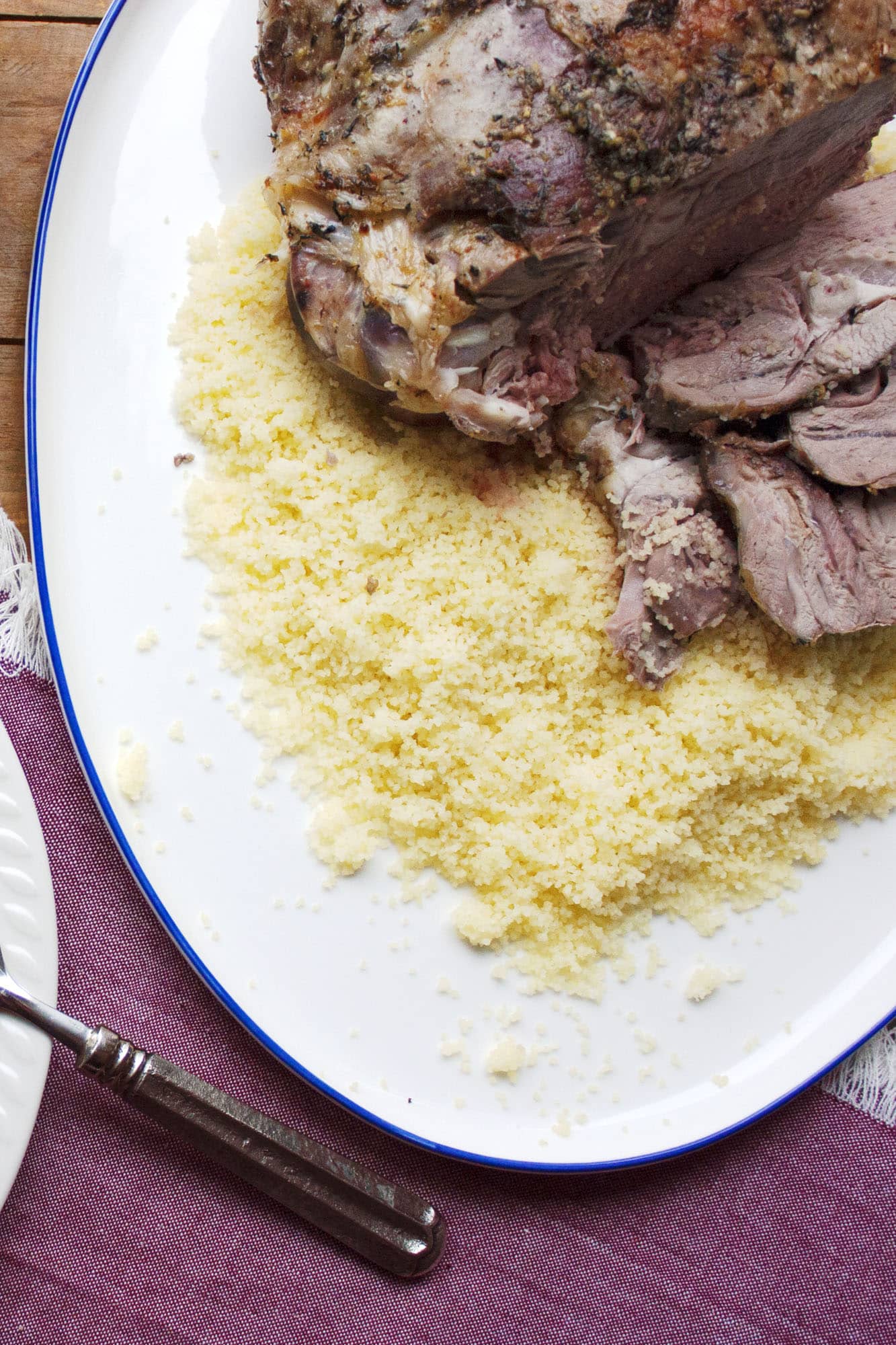 Partly sliced leg of lamb on a bed of couscous.