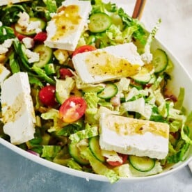 Greek Salad topped with Greek dressing in a bowl.