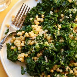 Couscous, kale, and lemon dressing salad on white plate.