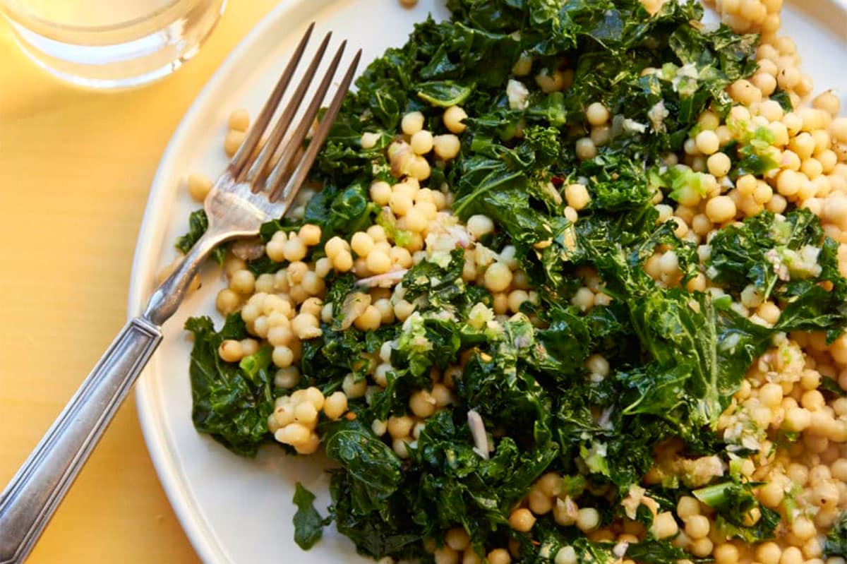 Couscous, kale, and lemon dressing salad on white plate.
