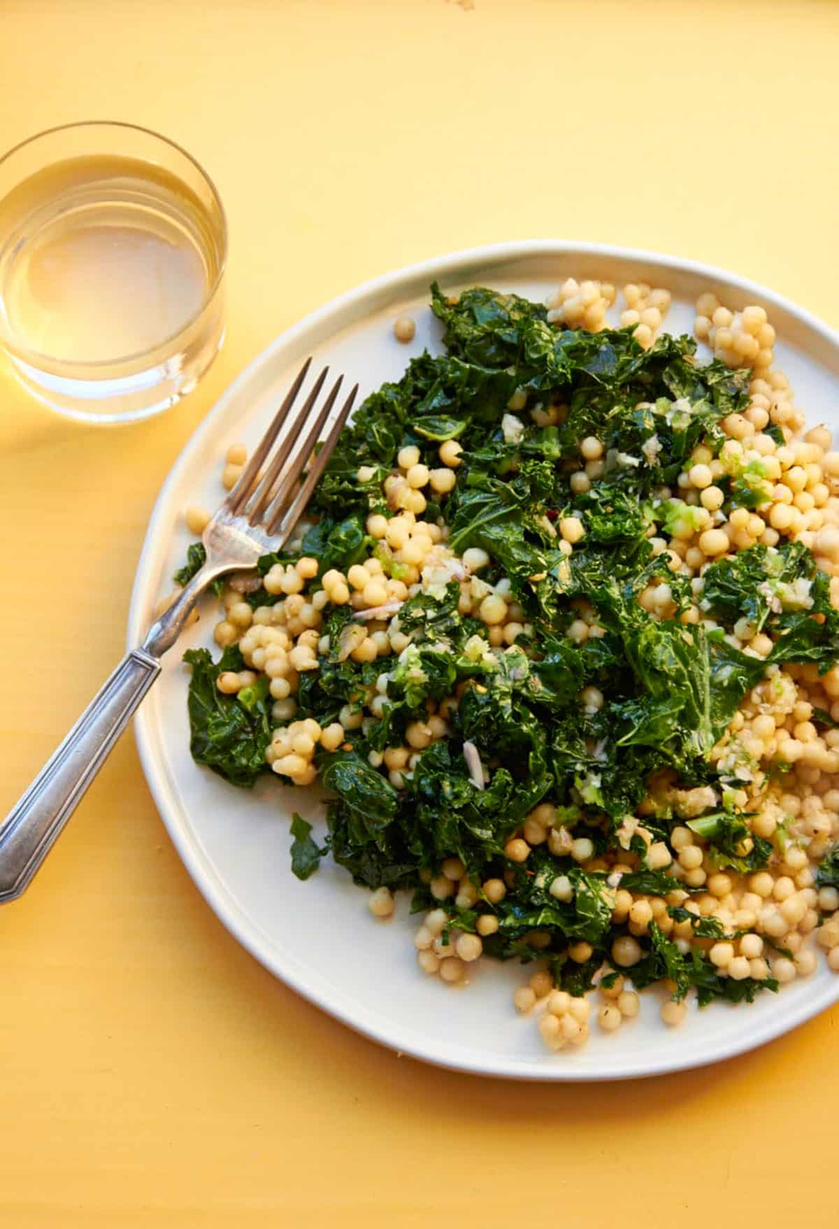 Couscous, kale, and lemon dressing salad on white plate.