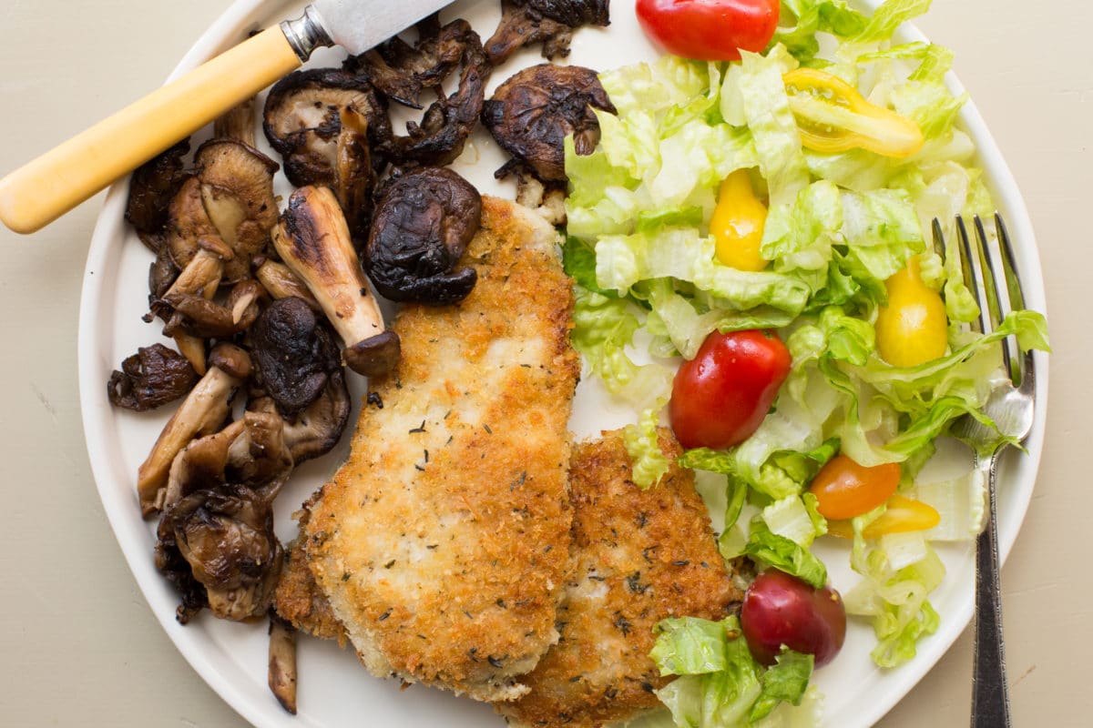 Pork Schnitzel with Sautéed Mushrooms on a plate with salad.