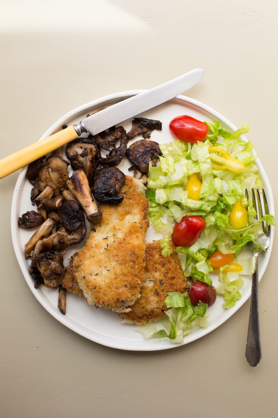 Plate of salad and Pork Schnitzel with Sautéed Mushrooms.