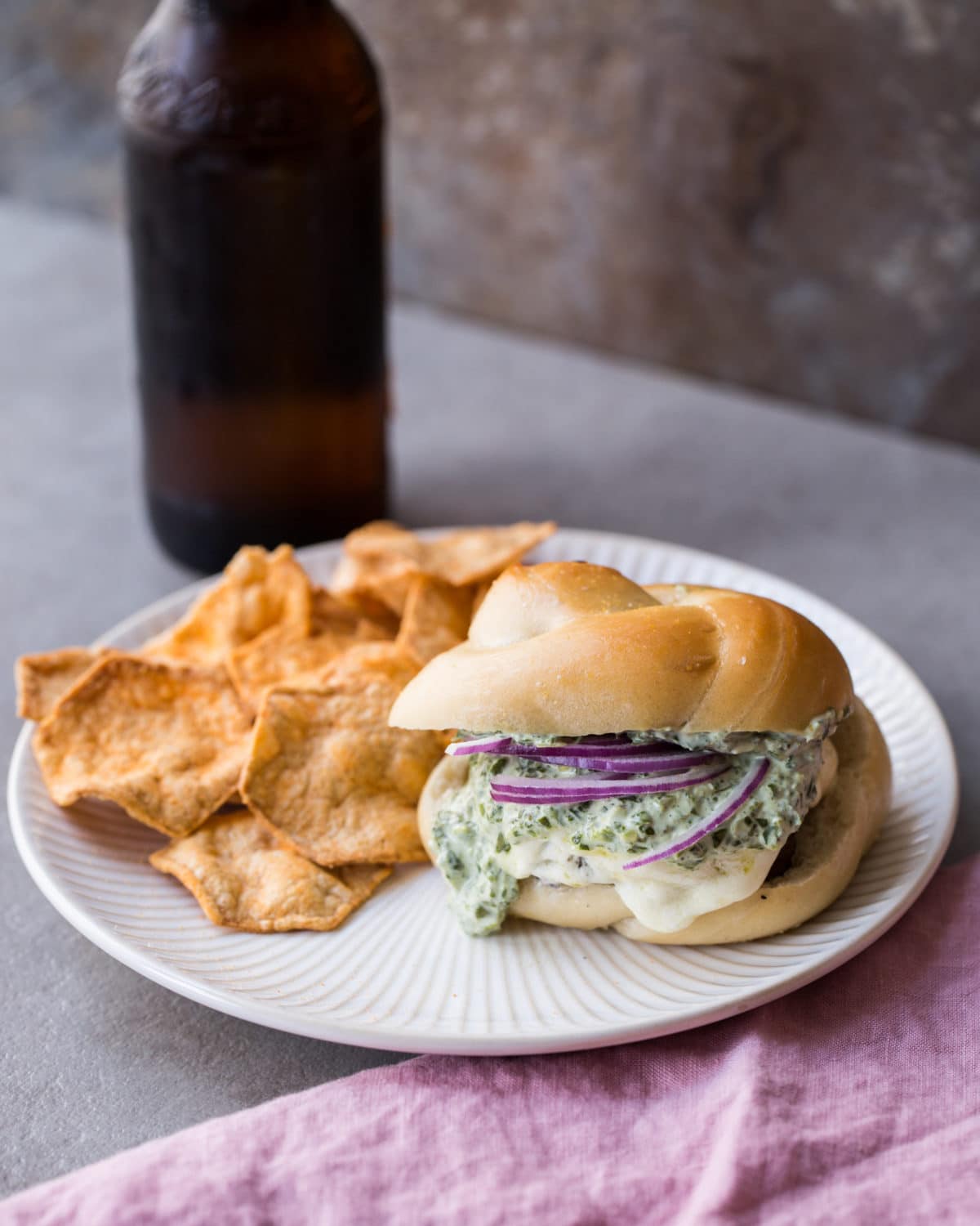 Chips on a plate with a Grilled Cheeseburger with Herb Sauce.