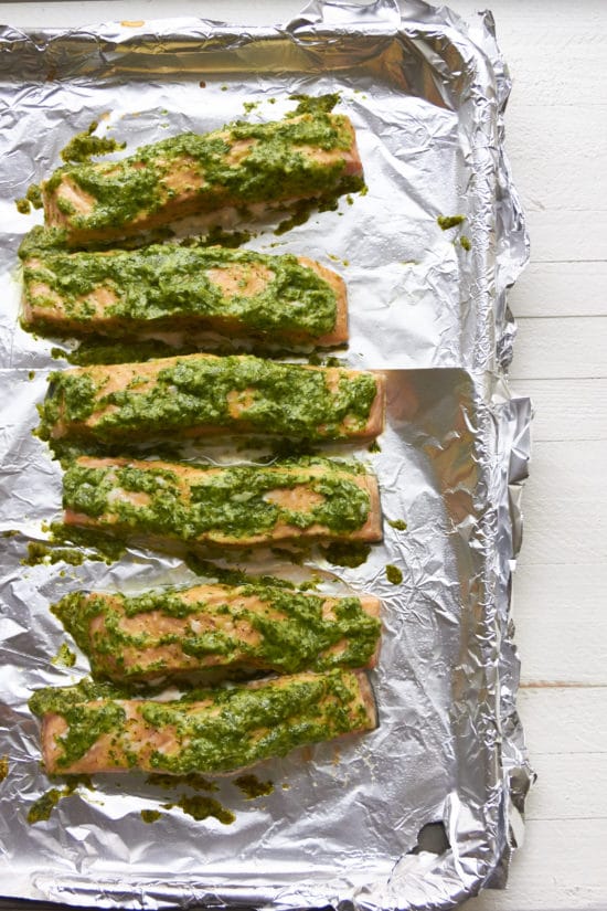 Several Herbed Salmon fillets on a baking sheet lined with foil.