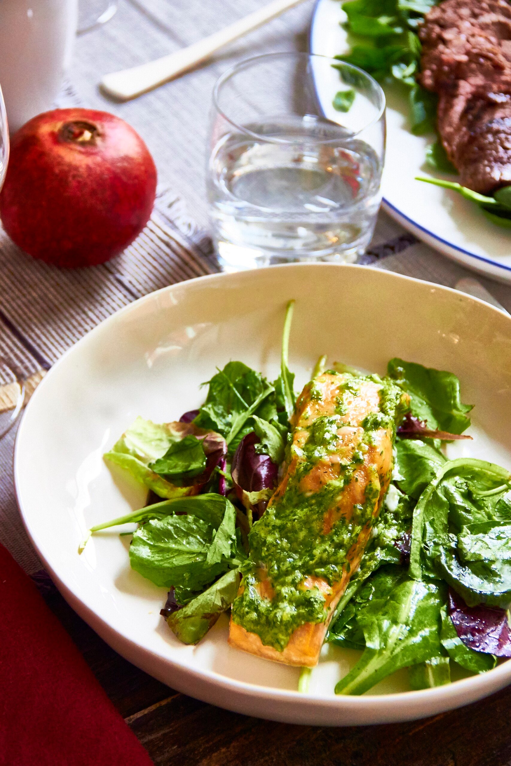 White plate of Herbed Salmon over a Soft Green Herby Salad.