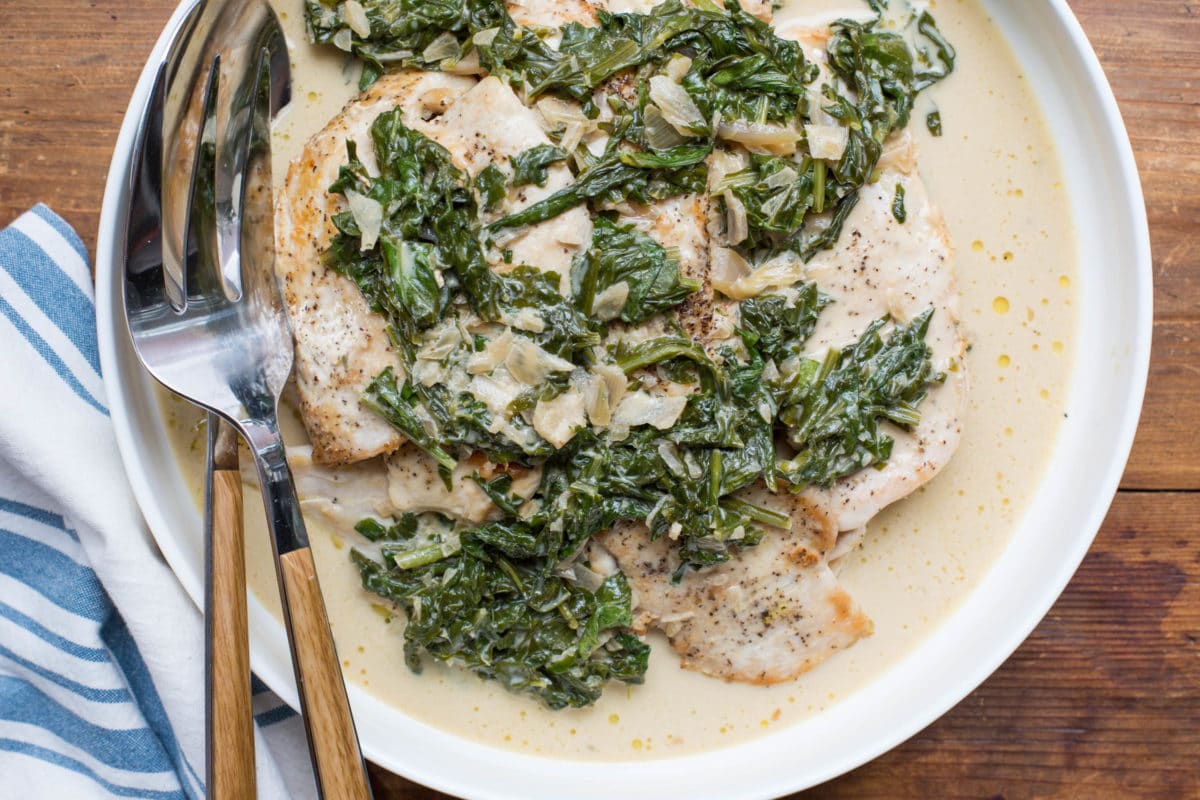 White dish of Chicken with Arugula and Mustard Pan Sauce with serving ware.