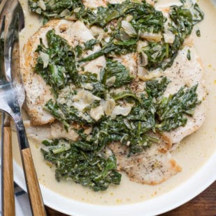 White dish of Chicken with Arugula and Mustard Pan Sauce with serving ware.
