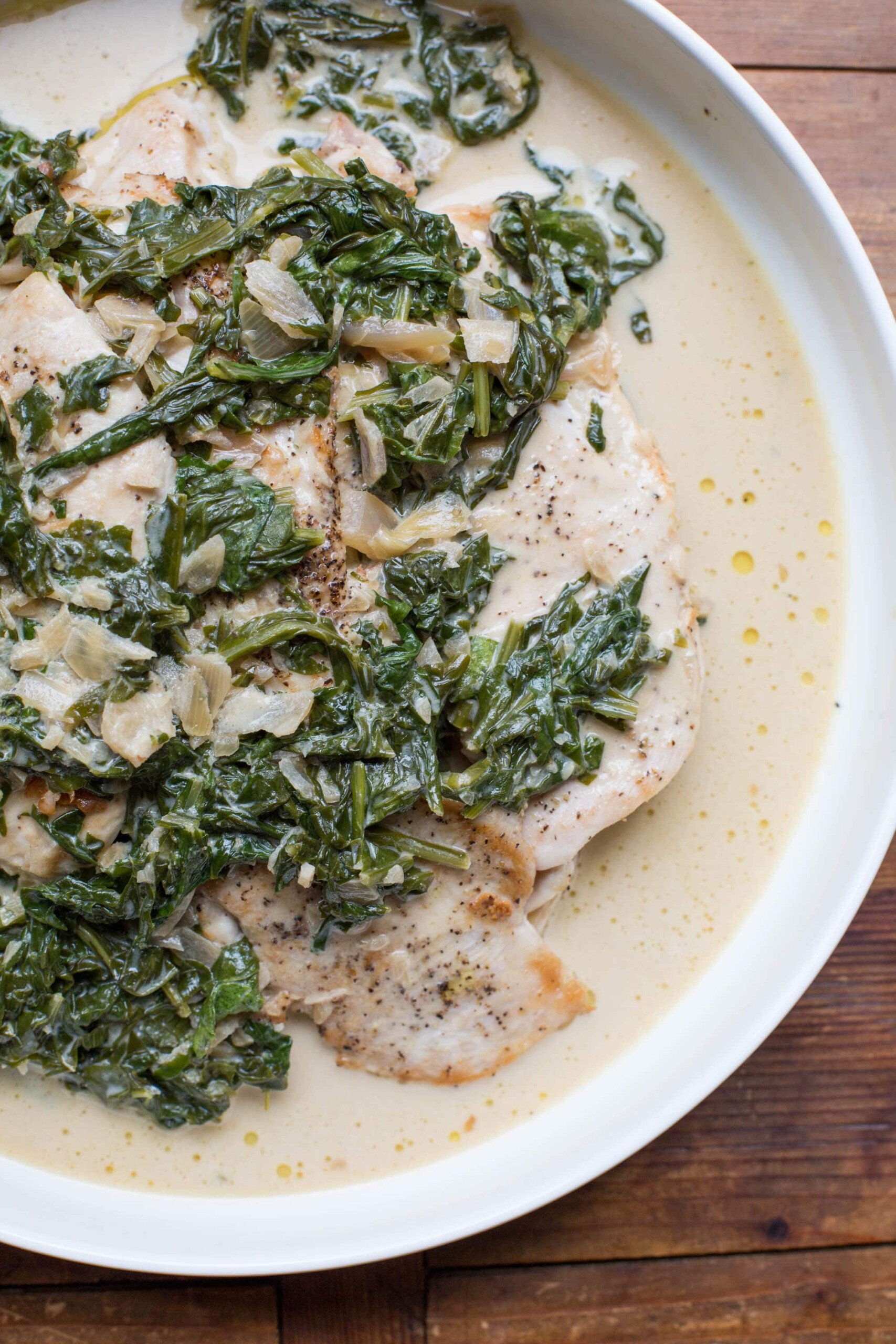 Arugula over Chicken with  Mustard Pan Sauce in a white dish.