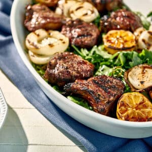 Grilled lamb chops in serving platter over salad.