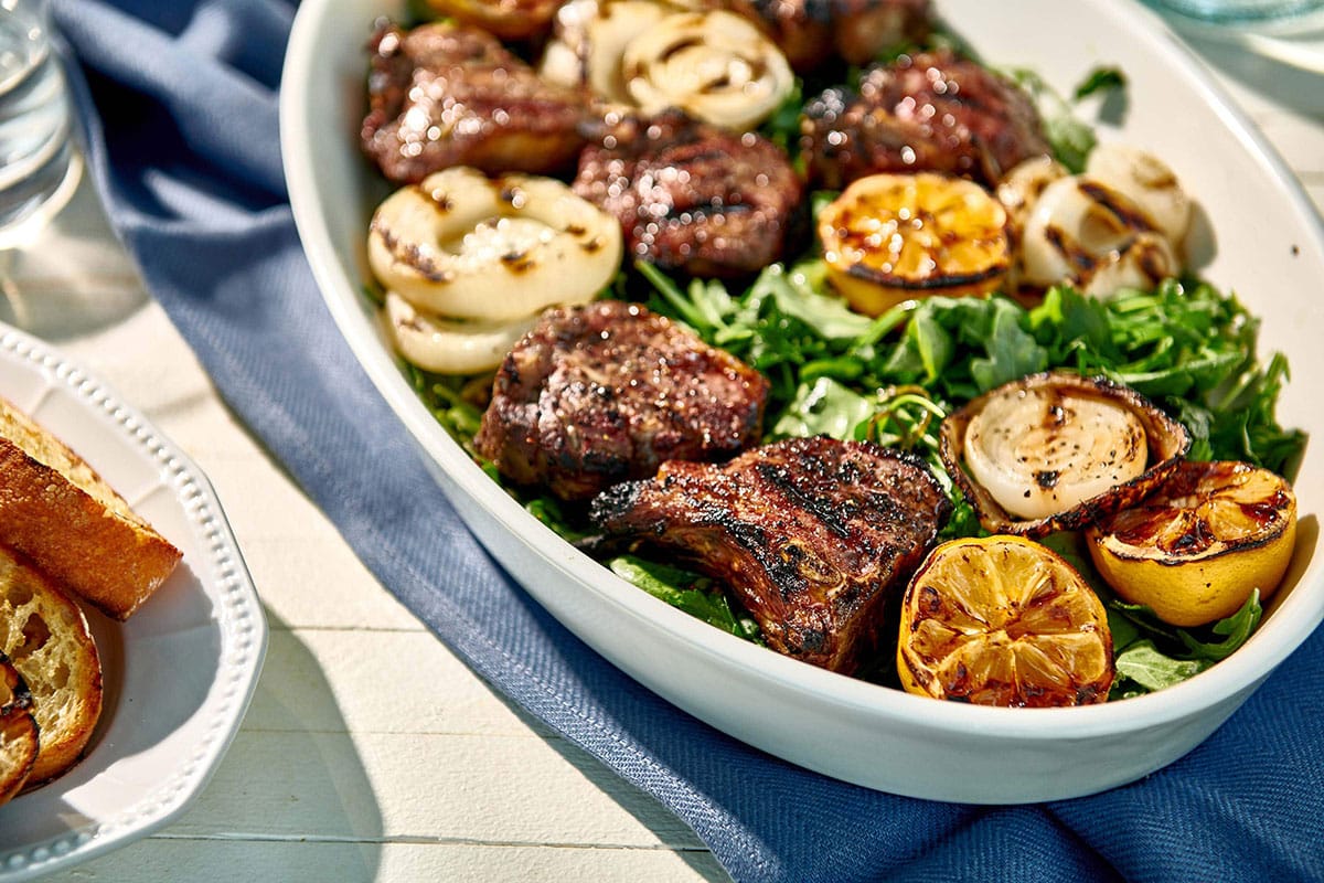 Grilled lamb chops in serving platter over salad.