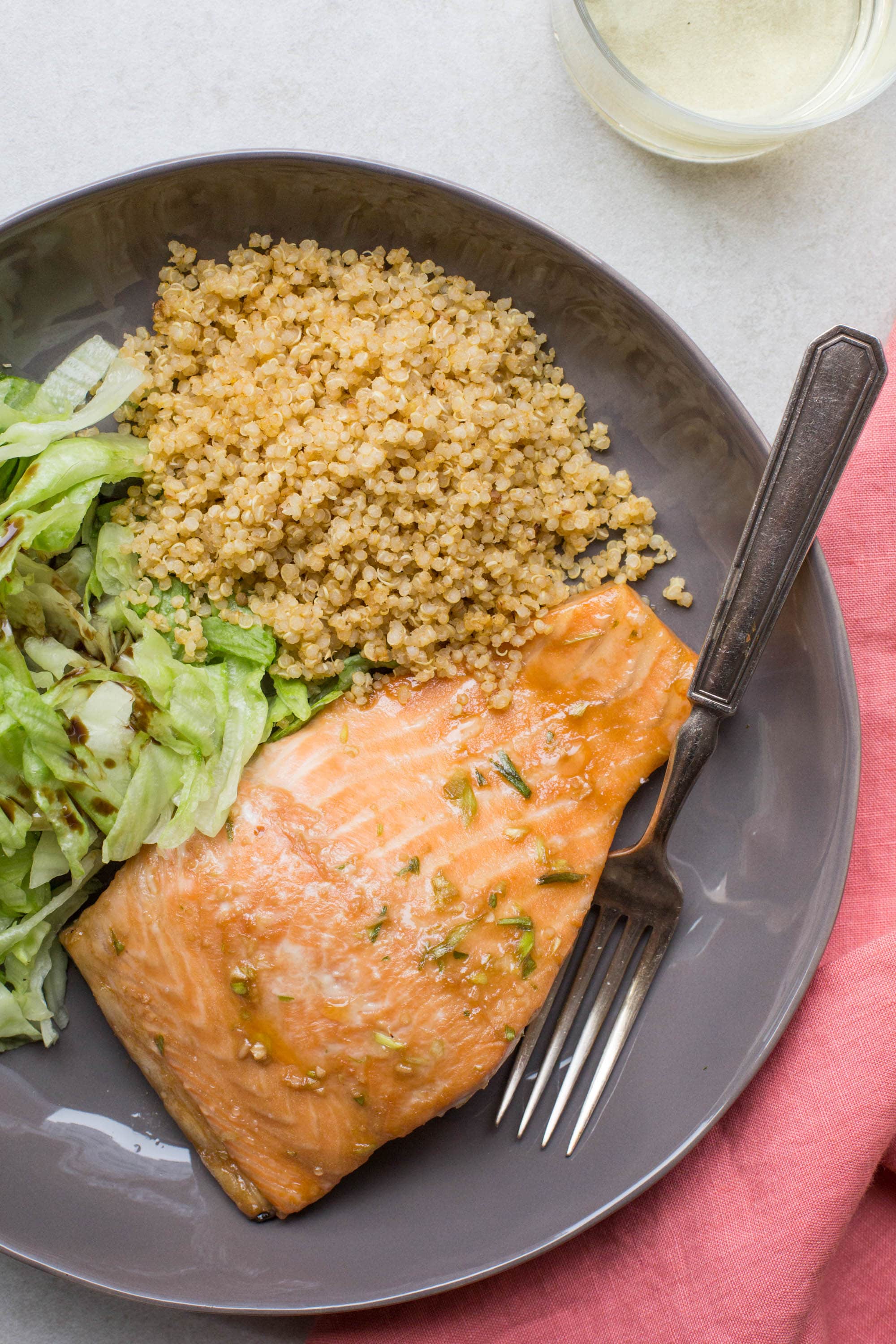 Hoisin-glazed salmon on grey plate with quinoa and lettuce salad.