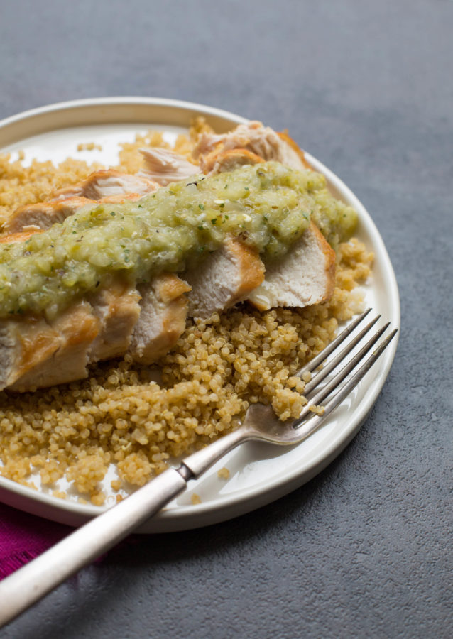 White plate of Pan-Seared Chicken Breasts with Roasted Tomatillo Salsa over couscous.