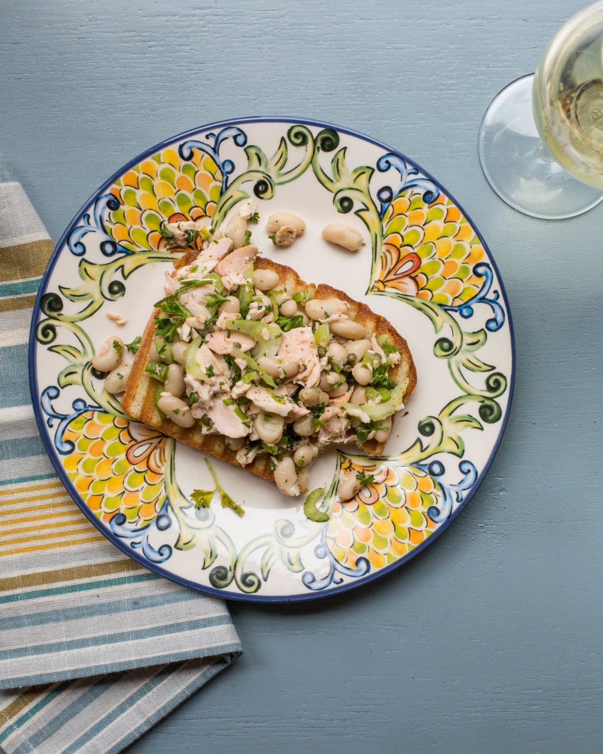 Colorful plate with a Salmon and White Bean Bruschetta missing a bite.