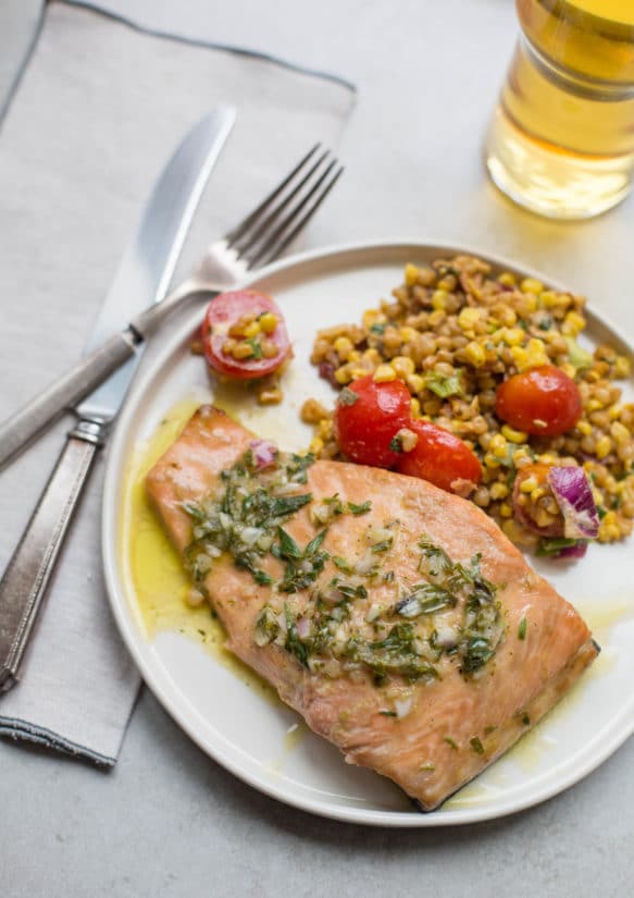 Salmon topped with Tarragon Vinaigrette on a plate with grain salad.