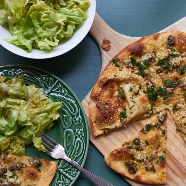 Clam Pizza on a wooden surface and on a plate with salad.