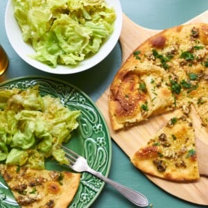 Clam Pizza and salad on a table.