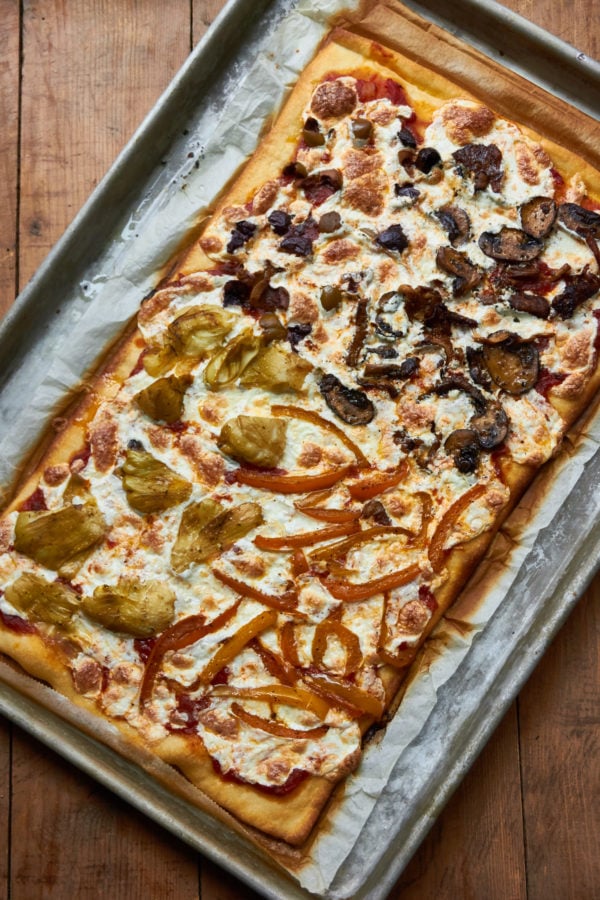 Pizza Quattro Stagioni on a lined baking sheet.