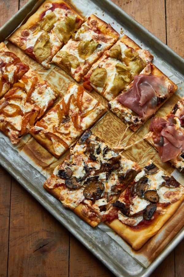 Sliced Pizza Quattro Stagioni on a lined baking sheet.