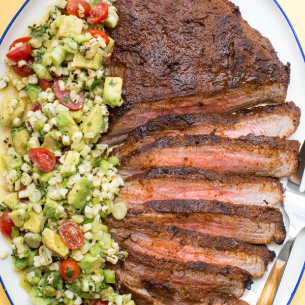 Partially-sliced Chili Rubbed Flank Steak with Corn, Tomato and Avocado Salad.