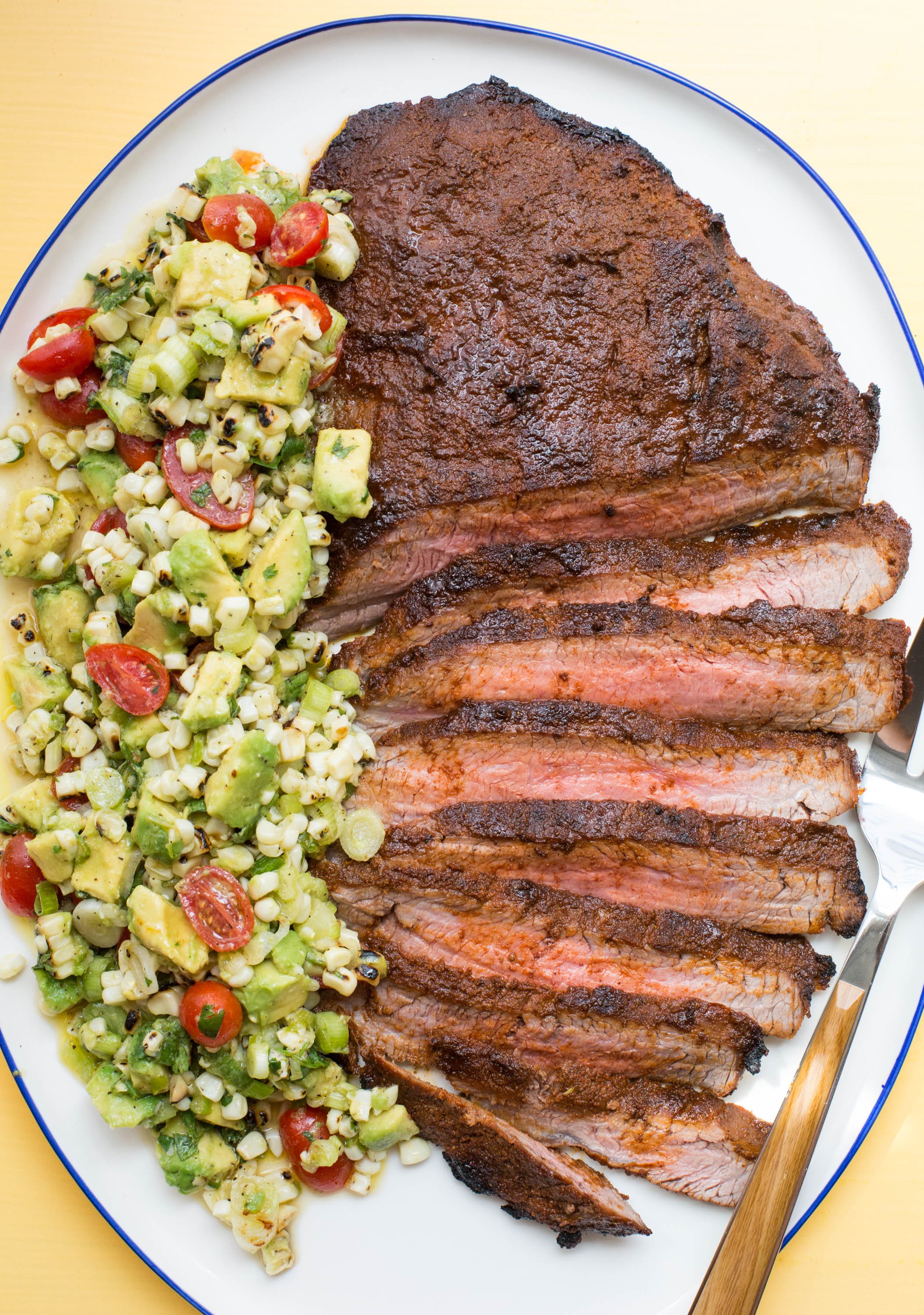 Partially-sliced Chili Rubbed Flank Steak with Corn, Tomato and Avocado Salad.