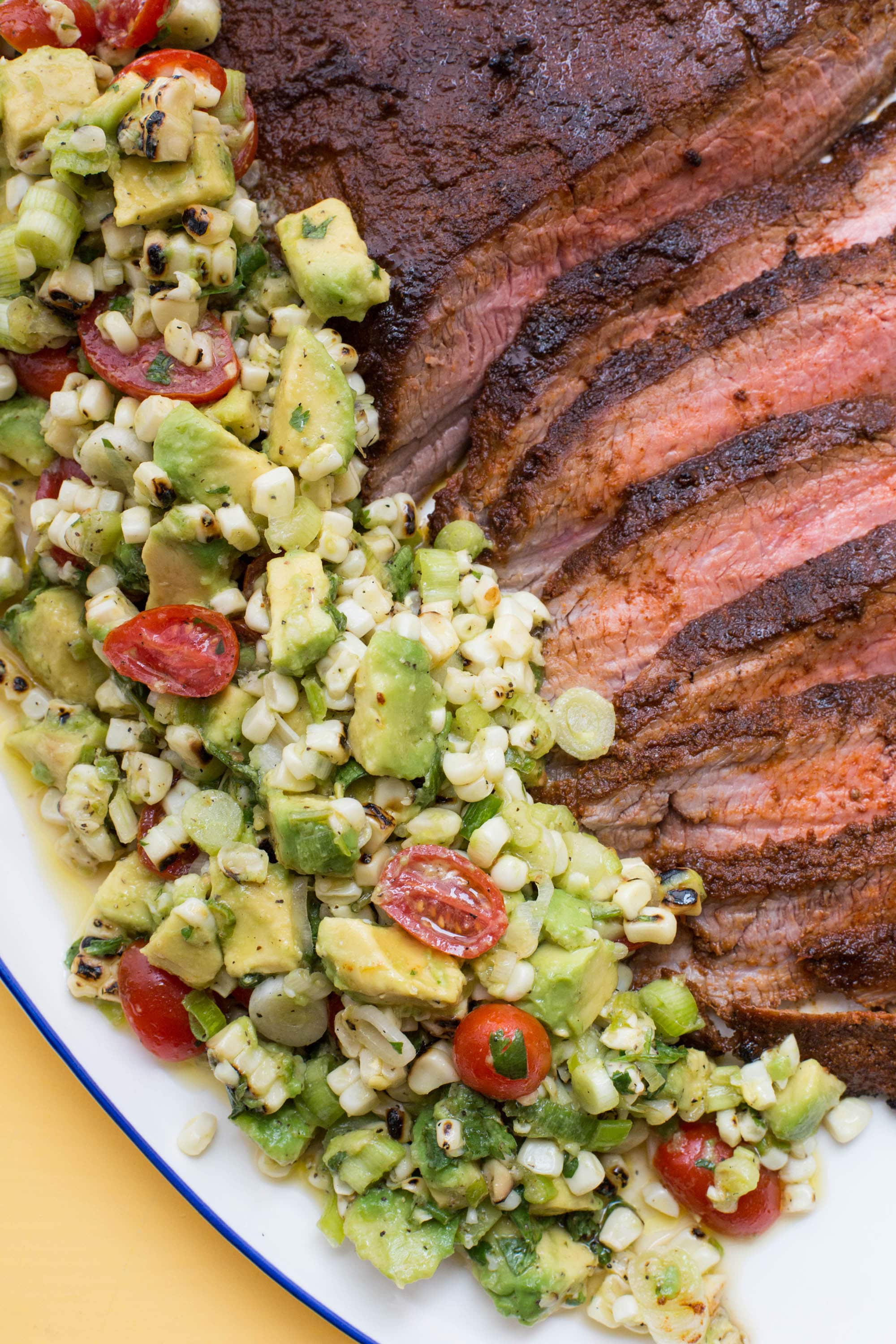 Slices of Chili Rubbed Flank Steak with Corn, Tomato and Avocado Salad.