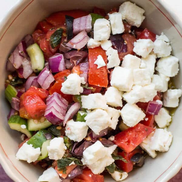 Tomato and cucumber salad with feta in bowl.